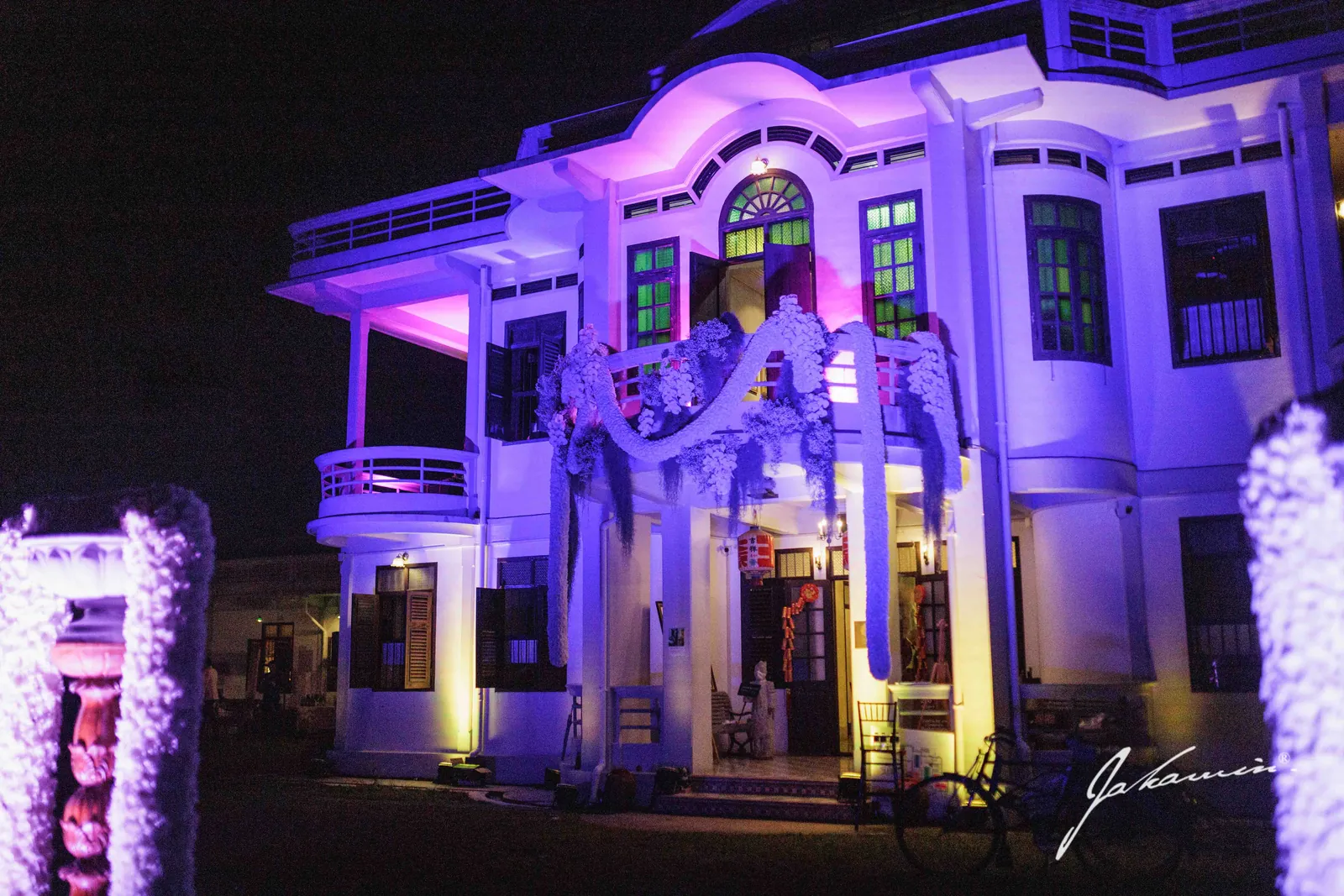 The 1936 mansion lit at night, dressed with florals for a wedding